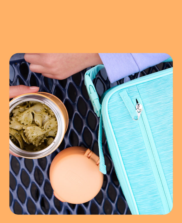 Open Thermos Food Jar with pasta and a Thermos Lunch box on a table. 