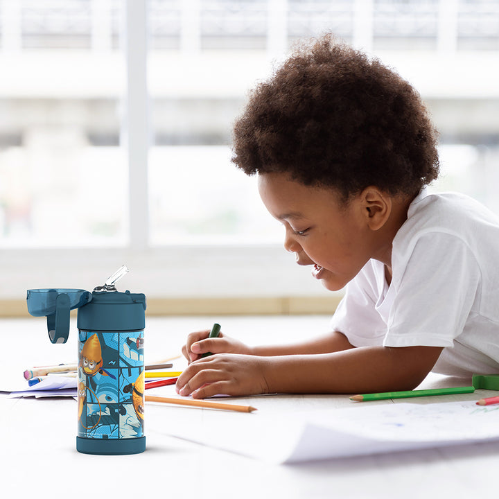 Boy sitting at a table coloring, with the 12 ounce Funtainer Despicable Me 4 Movie water bottle opened next to him.