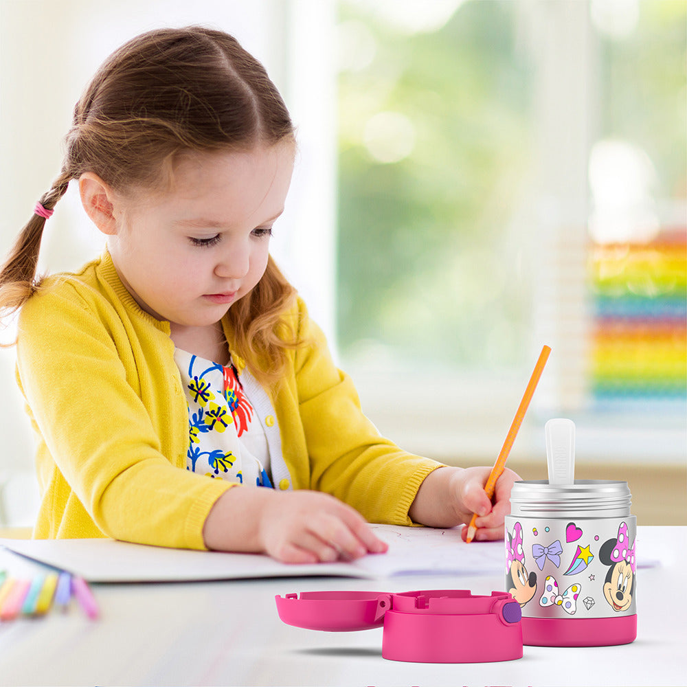 Girl sitting at table coloring with an open 10 ounce Funtainer food jar open in front of her. 