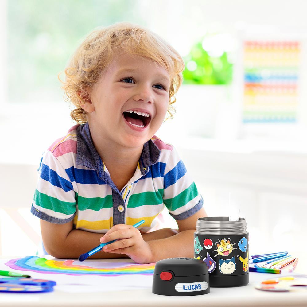 Boy sitting at table painting with an open 10 ounce Pokémon Funtainer food jar open in front of him.