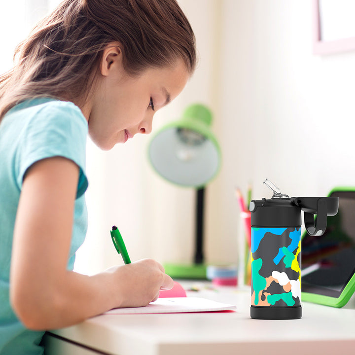 Girl sitting at a table doing homework, with a 12 ounce Neon Camo Pattern Funtainer water bottle opened next to her.