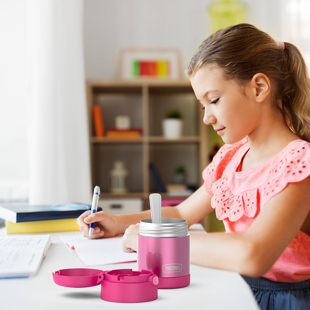 10 ounce Funtainer food jar open on a table next to a girl doing homework.