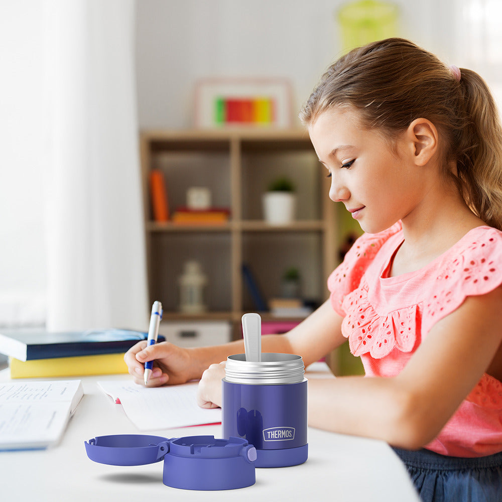 10 ounce Funtainer food jar open on a table next to a girl doing homework.