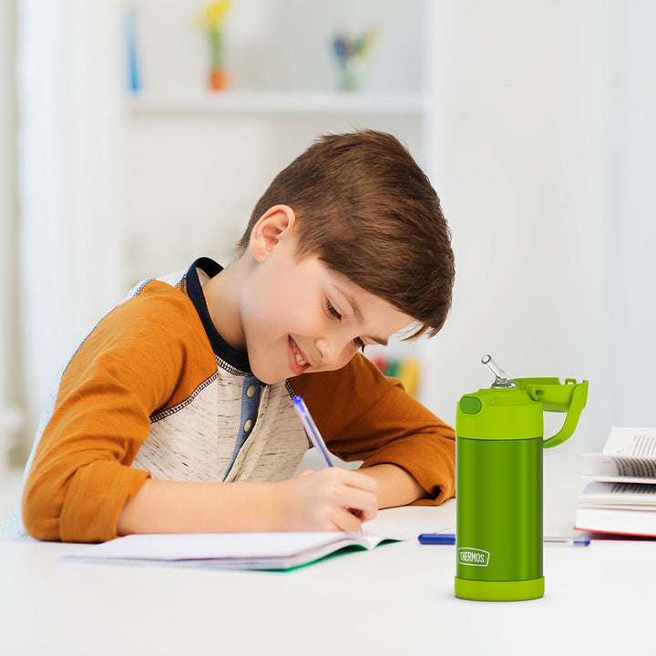 Boy sitting at a table doing homework, with the 12 ounce Funtainer lime water bottle opened next to him.