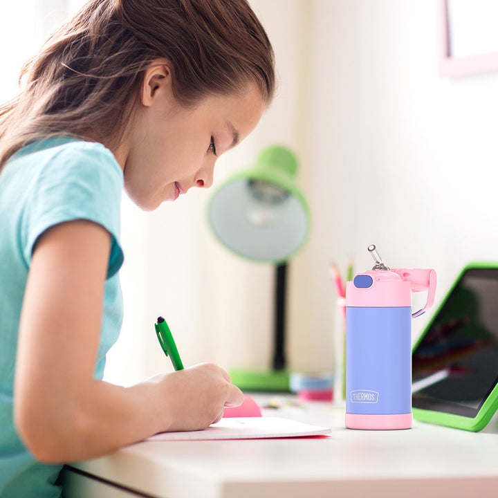 Girl sitting at a table doing homework, with a 12 ounce purple and pink Funtainer water bottle opened next to her.